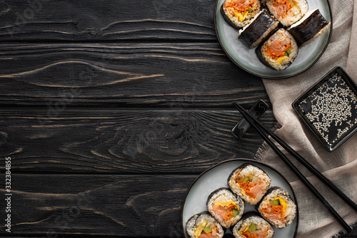 top view of chopsticks and sesame oil near plates with gimbap on wooden surface