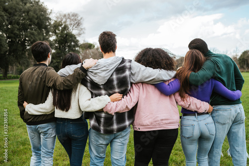 Group of young friends at park at sunset hugging each other - Teenagers in a moment of unity, fraternity, help and team building