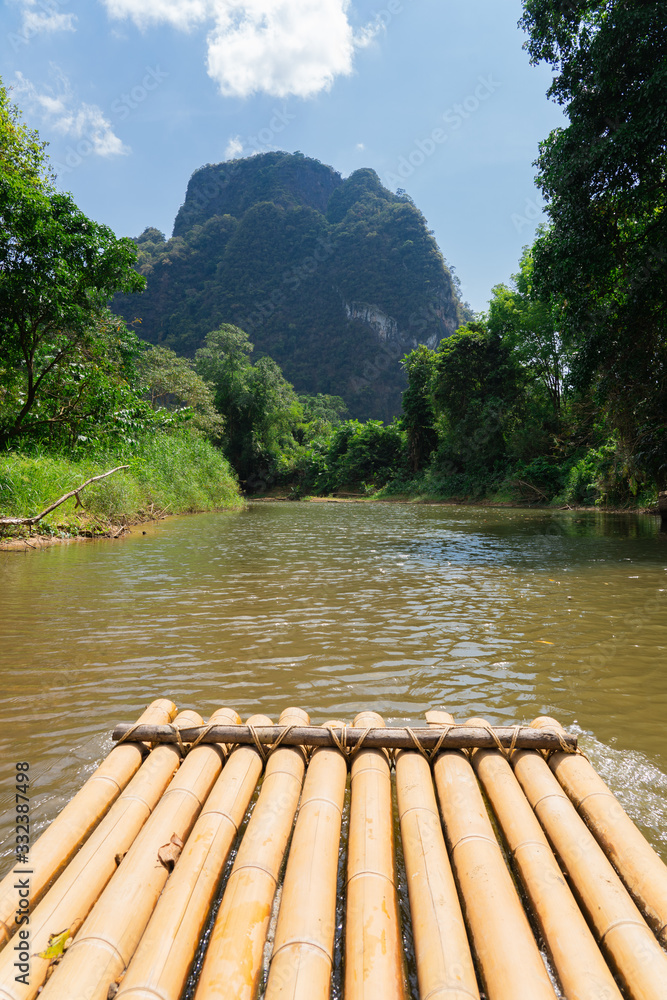 Bamboo rafting by a picturesque river in tropical jungles, surrounded by mountains