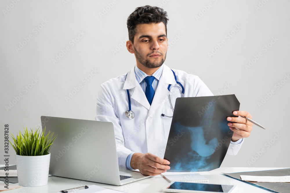 Handsome young doctor looking at x-ray scan Handsome young doctor looking at x-ray scan