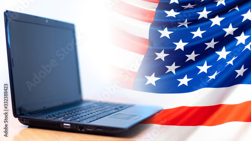 A laptop next to the USA flag. Flag of the United States close up. Concept - US government sites. Concept - Sat on Migration to America. Relocation to the United States. American Internet segment