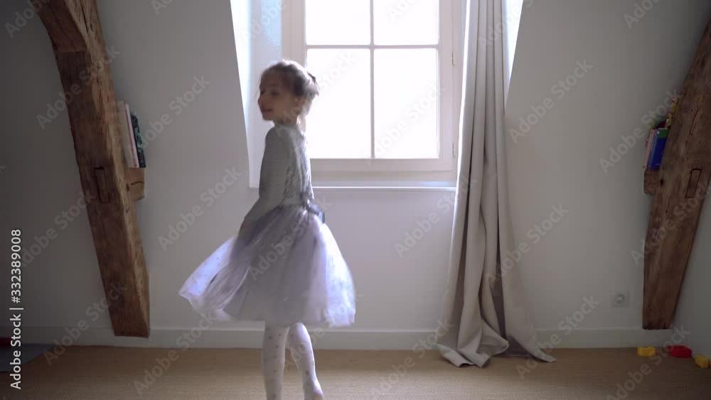 Little girl with magical light jumping around in circles having fun and playing. Sweet joyful blonde kid dancing in her bedroom dressed with ballerina dress. Happy lifestyle with children at home. Little girl with magical light jumping around in circles having fun and playing. Sweet joyful blonde kid dancing in her bedroom dressed with ballerina dress. Happy lifestyle with children at home.