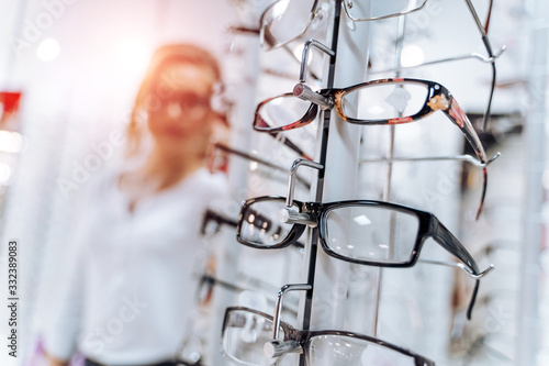 Stand with glasses in the store of optics. Woman chooses glasses.