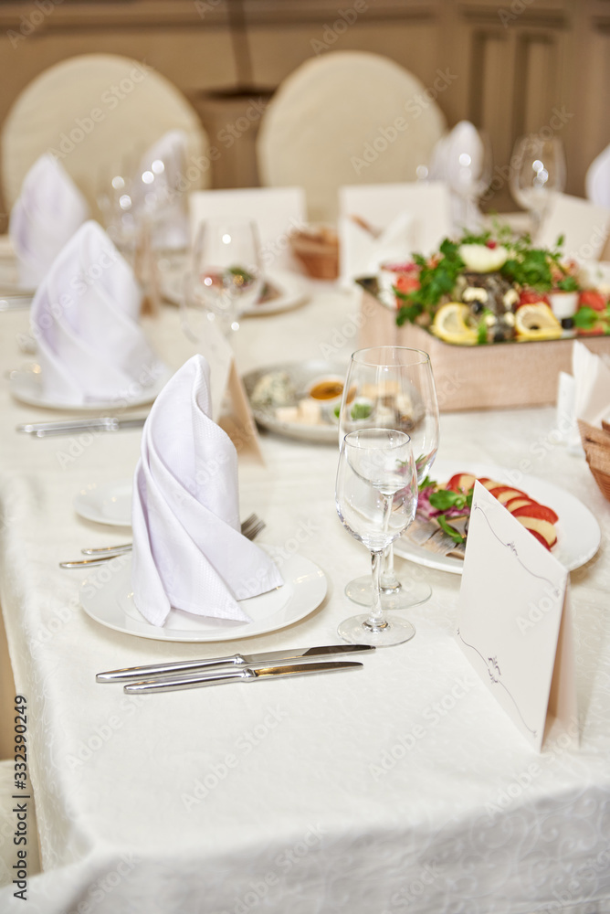 Table set with blank guest card, plate with serviette and cutlery on table, copy space. Place setting at wedding reception. Table served for wedding banquet in restaurant