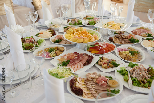 Table served for wedding banquet in restaurant. Table set with plates, white serviettes and cutlery on table, copy space. Place setting at wedding reception