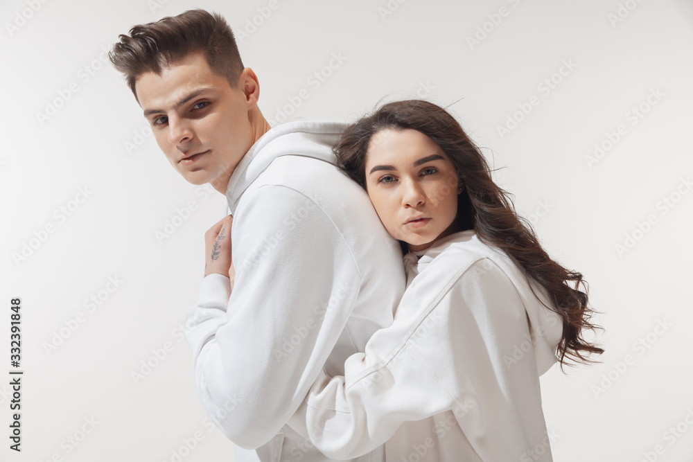 Tender hug. Trendy fashionable couple isolated on white studio background. Caucasian woman and man posing in basic minimal unisex clothes. Concept of relations, fashion, beauty, love. Inclusive. Tender hug. Trendy fashionable couple isolated on white studio background. Caucasian woman and man posing in basic minimal unisex clothes. Concept of relations, fashion, beauty, love. Inclusive.