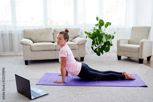 Obraz na plátně Young woman practicing yoga with laptop at home indoor, copy space
