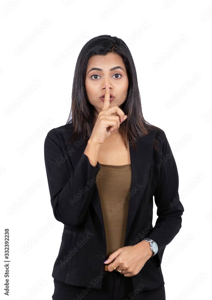 Confident young Indian businesswoman with finger on lips over white background Confident young Indian businesswoman with finger on lips over white background