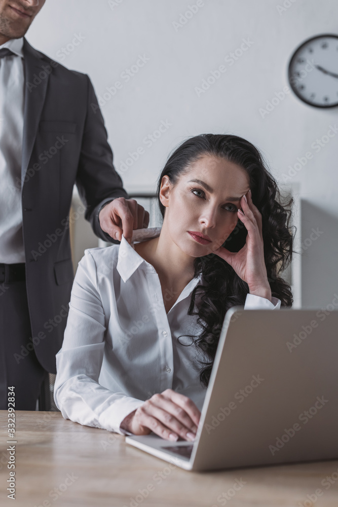 cropped view of businessman touching blouse of bored secretary sitting at workplace cropped view of businessman touching blouse of bored secretary sitting at workplace