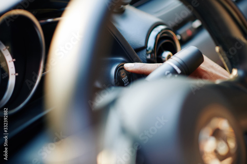 Close-up image of female driver pushing launch control button in modern car
