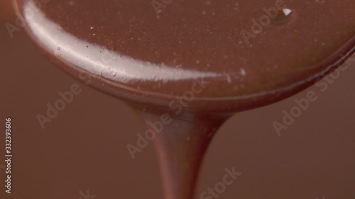 Slow motion closeup melted dark chocolate dripping from spoon photo