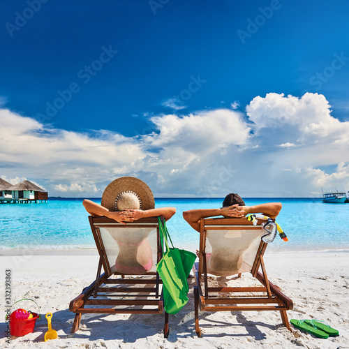 Couple in sun beds on a tropical beach