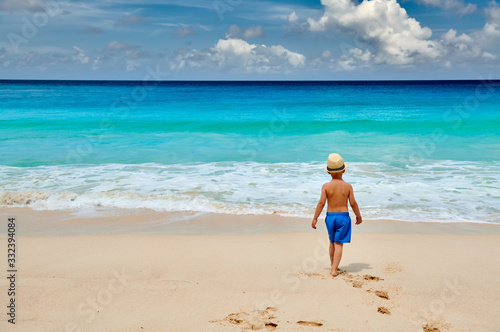 Three year old toddler boy walking on beach