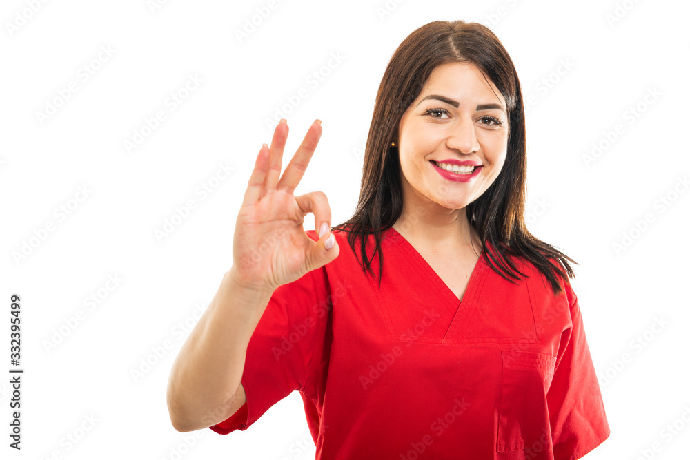Portrait of beautiful doctor wearing scrubs making ok gesture Portrait of beautiful doctor wearing scrubs making ok gesture