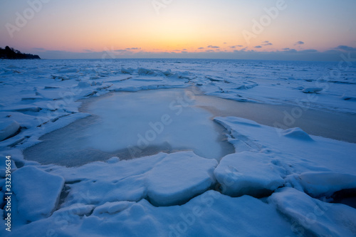 Sunset in the orange sky over the blue ice of the Baltic Sea