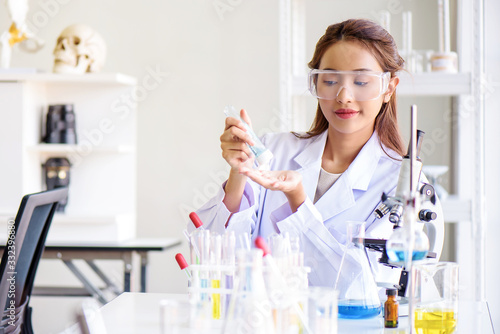 Attractive happiness Scientist woman using alcohol hand gel cleaning her hand at laboratory with lab glassware on the table. Science or medical research and development new antivirus concept.