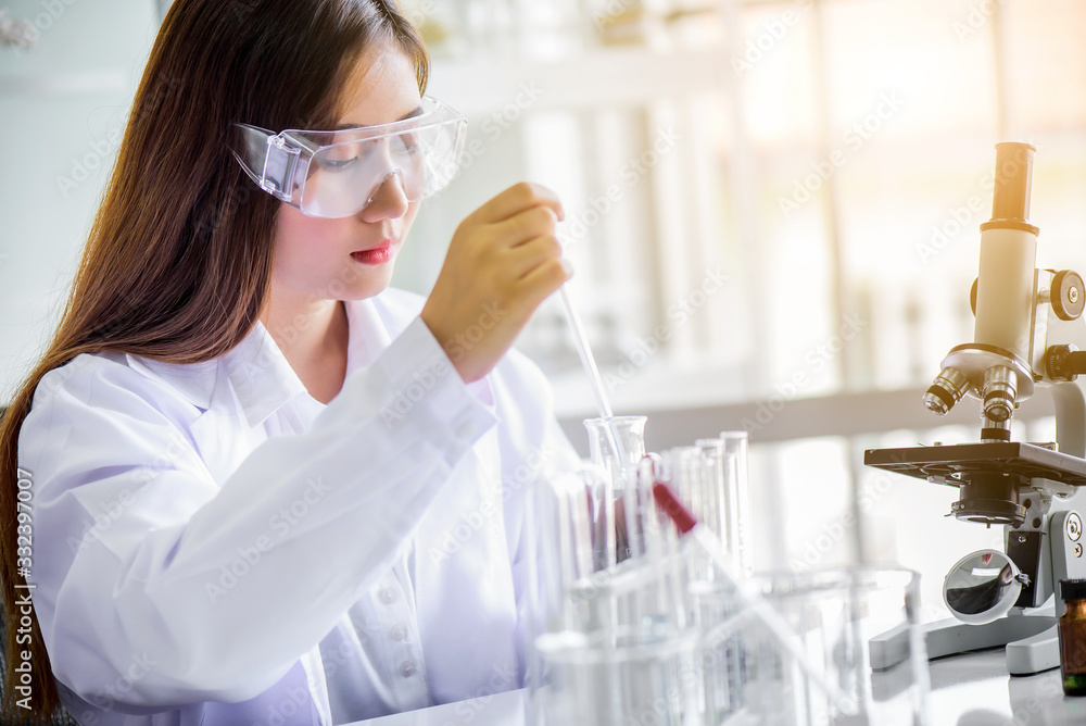 Attractive happiness scientist woman using microscope testing sample at laboratory with lab glassware. Science or medical research and development new antivirus or Covid-19 vaccine concept. Attractive happiness scientist woman using microscope testing sample at laboratory with lab glassware. Science or medical research and development new antivirus or Covid-19 vaccine concept.