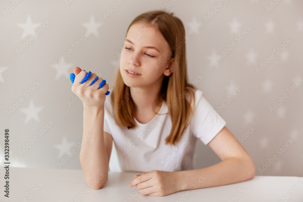 The young girl squeezes the blue slime with her hand and looks at it with a smile. Toy for developing fine motor skills, the toy is from the slime The young girl squeezes the blue slime with her hand and looks at it with a smile. Toy for developing fine motor skills, the toy is from the slime