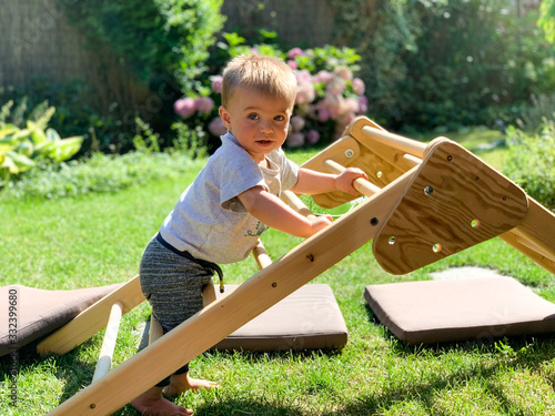 Baby learning to stand and climb on a wooden structure