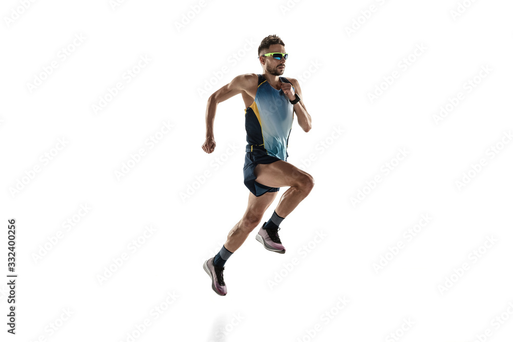 Triathlon male athlete running isolated on white studio background. Caucasian fit jogger, triathlete training wearing sports equipment. Concept of healthy lifestyle, sport, action, motion. Side view.