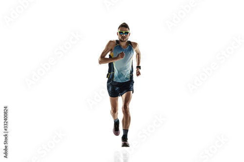 Triathlon male athlete running isolated on white studio background. Caucasian fit jogger, triathlete training wearing sports equipment. Concept of healthy lifestyle, sport, action, motion. Time check. © master1305