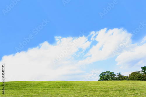 雲と青空を背景にした緑の丘。背景用素材