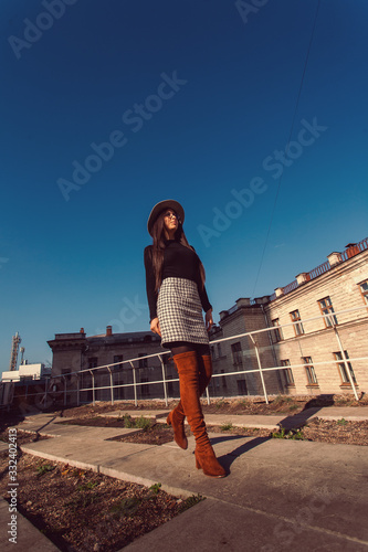 Obraz na płótnie Young pretty stylish girl walking along the street. Girl model in hat walks along the street. w salonie