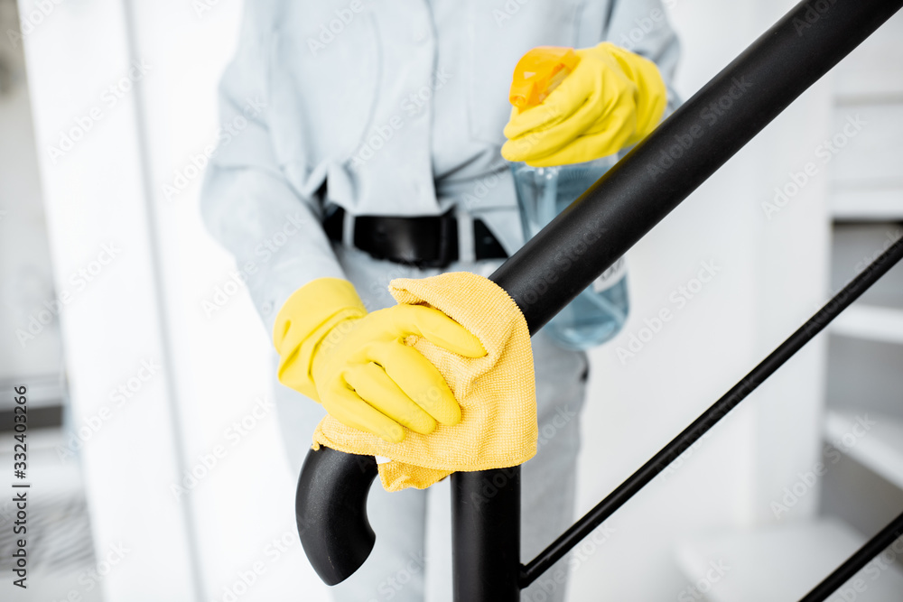 Woman in protective gloves disinfecting stair railings while cleaning at home, close-up view on hands - obrazy, fototapety, plakaty 