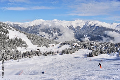 Ski resort by winter with skiing and snowboarding people on the slope 
