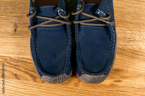 Closeup top view photography of details of casual blue leather mocassins with brown shoelaces.