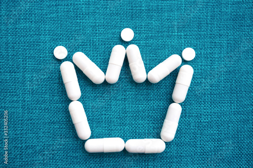 The crown sign is laid out of white capsules on a blue background.  The concept of the treatment of dangerous deadly coronavirus. Free space