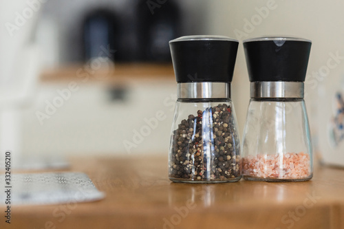 Glass salt and pepper shakers on wooden board