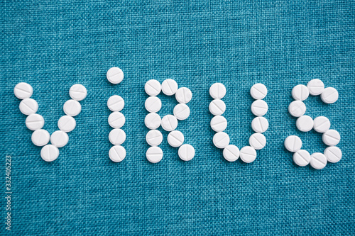 The word virus laid out from white capsules on a blue background. The concept of the treatment of dangerous deadly coronavirus.