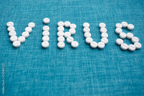 The word virus laid out from white capsules on a blue background. The concept of the treatment of dangerous deadly coronavirus. Copy space