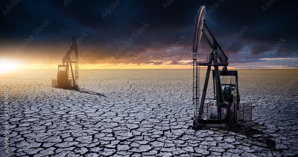 Oil rig in the desert on a background of a dramatic sky. Symbol of the crisis in the oil industry - obrazy, fototapety, plakaty 