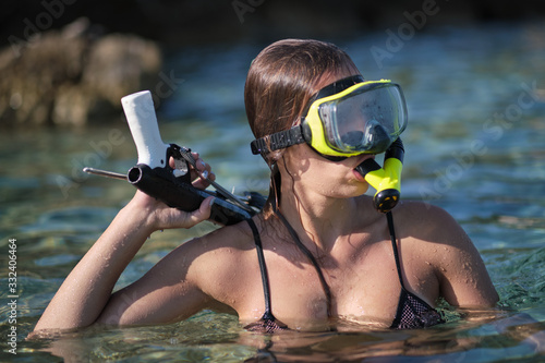 A woman in a bikini hunts with a crossbow