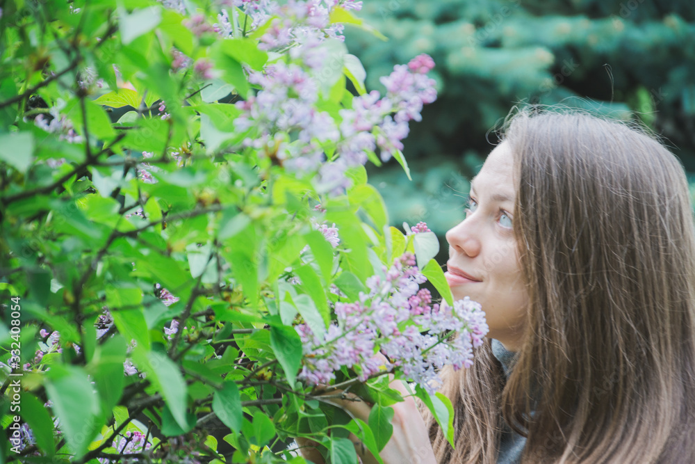 Fototapeta premium Young Girl Posing Near Lilac Bushes