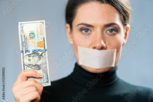 girl in black with a sealed mouth and plenty of cash in hand. silent witness of a crime. bribery and bias. concept of corruption. censorship photo