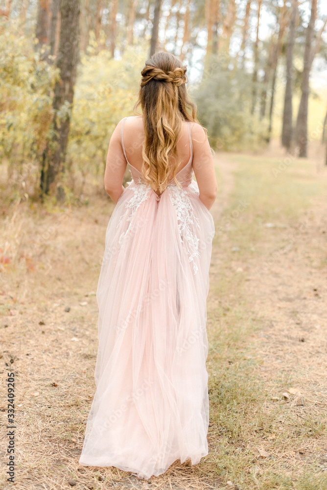 bride in pink dress walking in forest