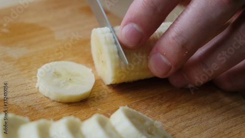 Male hand cuts a banana on the board, close-up photo