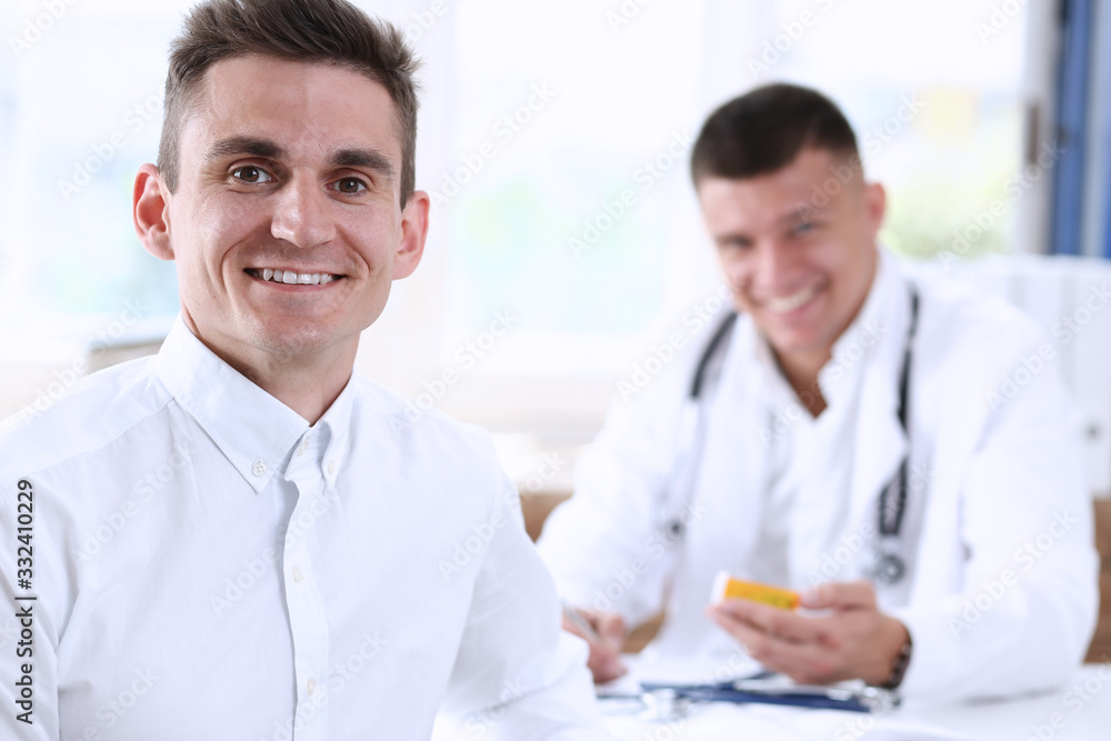 Satisfied happy handsome smiling male patient with doctor at his office. High level and quality medical service, therapeutist consultation, work and career, physical, healthy lifestyle concept Satisfied happy handsome smiling male patient with doctor at his office. High level and quality medical service, therapeutist consultation, work and career, physical, healthy lifestyle concept