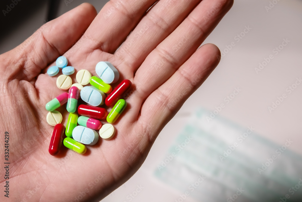 Colorful medicine in hand with mask and white background Colorful medicine in hand with mask and white background