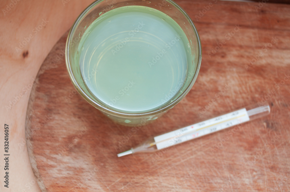 A glass of eucalyptus alcohol gargle and a thermometer. We treat a sore throat. Lower the temperature. A glass of eucalyptus alcohol gargle and a thermometer. We treat a sore throat. Lower the temperature.