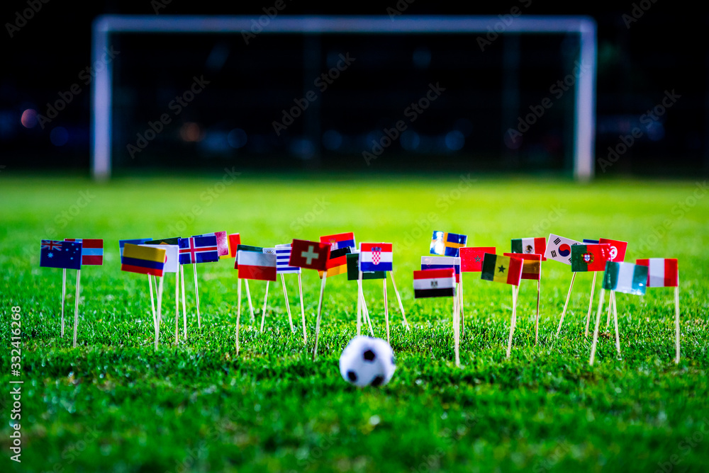 Obraz premium Football ball on green grass and all national flags of World Cup in Russia 2018.