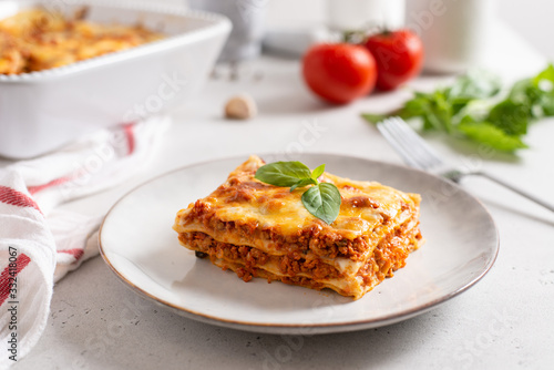 Piece of tasty hot lasagna served with a basil leaf on a gray plate. Italian cuisine, menu, recipe. Homemade meat lasagna. Close up