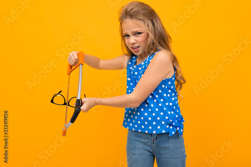 teenager girl breaks glasses in hands on a yellow background with copy space