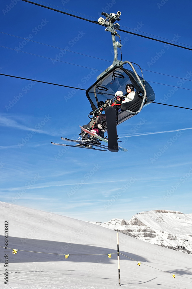 Family on ski and snowboards in the cable car cabin