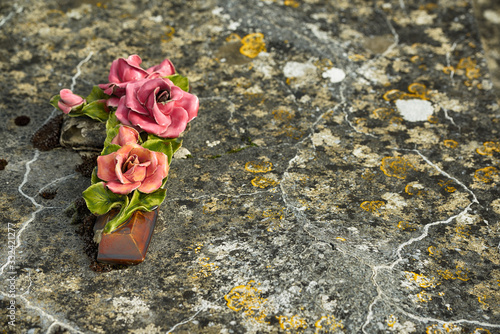 Photography Close up at artificial porcelain flowers on ancient grave.