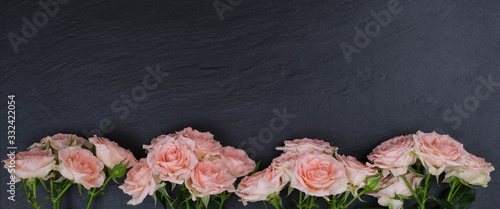 Fresh pink roses on a black background made of natural stone. Copy space
