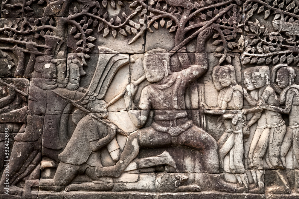 Fototapeta premium War scene on 12th century relief of Bayon temple, Cambodia. Historical artwork on wall of Khmer landmark in Angkor. UNESCO world heritage site